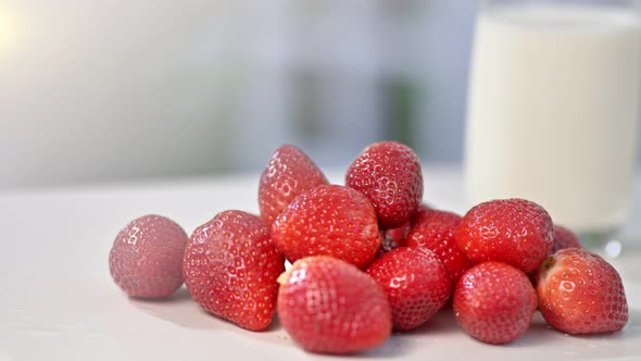 Closeup of Few Fresh Organic Strawberries on White Table Surface in Background Glass of Milk