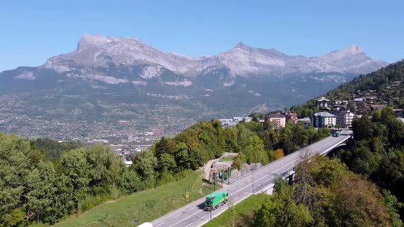Flying backwards over a bridge, nice mountain range in the background. Village of Saint Gervais les