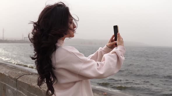 Beautiful woman takes pictures of the sea with her phone