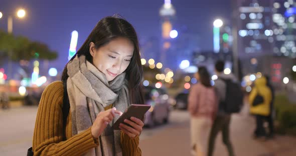 Woman working on cellphone in the city at night