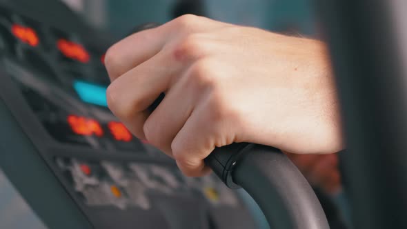 Athlete Trains on an Elliptical Trainer at Home Watching Heart Rate on Monitor