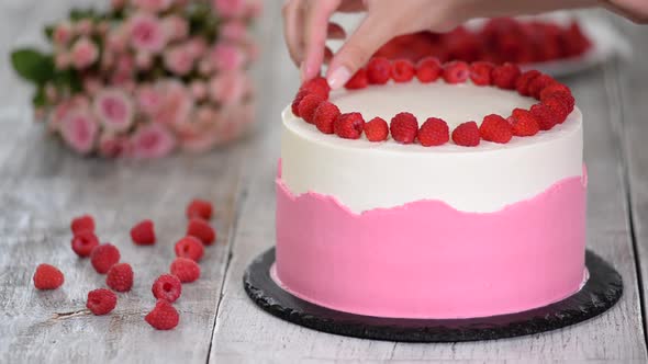 Chef decorate the cake with raspberries.	