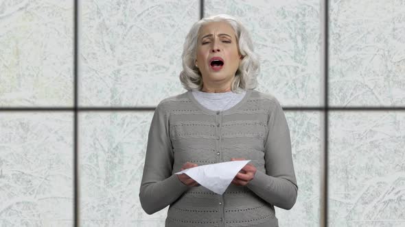 Sick Mature Woman Sneezing in Tissue