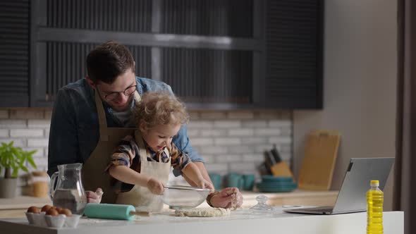 Loving Father is Laughing When His Little Son is Playing with Tableware and Dough During Cooking