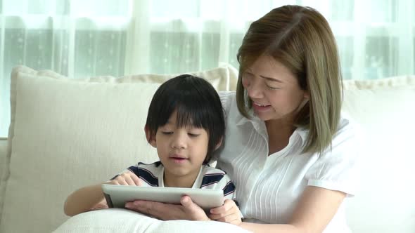 Asian Child And His Mother Using Tablet Together