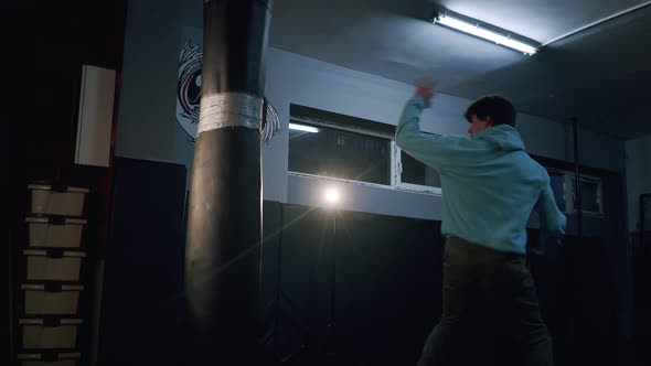 Alone Boxer Hits Punching Bag in Dark Gym in Slow Motion