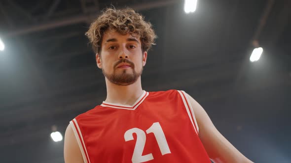 Portrait of an Caucasian Man Basketball Player Serious Looking at the Camera and Holds the Ball in