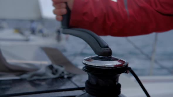 Closeup up of Yachtsman hands pulling rope  on sailboat, yacht detail, working on water transport