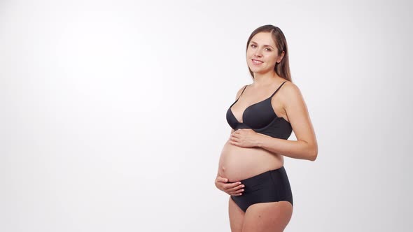 Young, happy and healthy pregnant woman in front of white background.