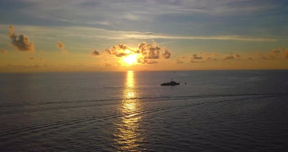 Aerial flight at spectacular sunset over ocean and big boat in Mabul, Malaysia