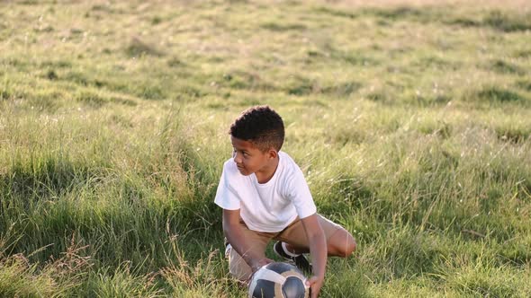 African Boy Playing Football Alone in a Summer Field