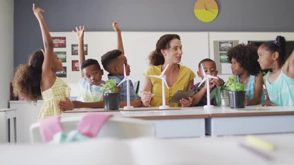 Video of happy caucasian female teacher and class of diverse pupils studying ecology in classroom