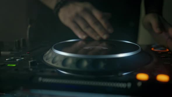 Hands of Unknown DJ Touching Vinyl Plate Mixing and Scratching Music Using Mixer Controller Rocking