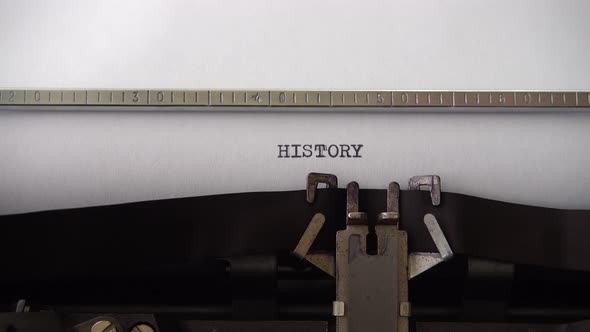 Typing word HISTORY on retro typewriter. Close up.