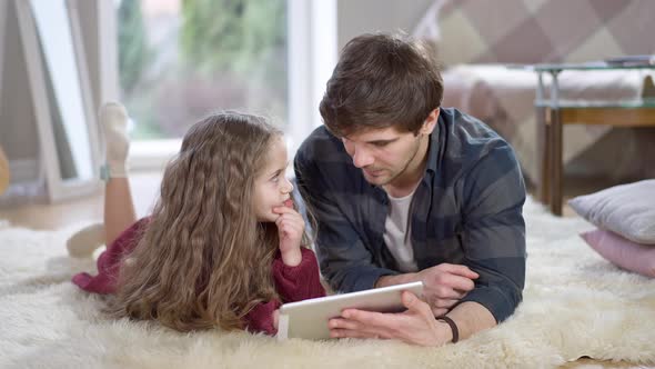 Portrait of Relaxed Young Man and Little Girl Using Tablet and Talking