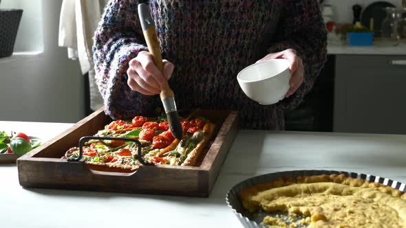 woman prepares focaccia with whole carrots and asparagus
