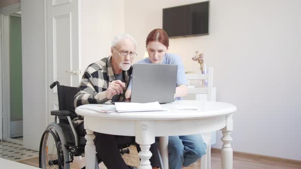 The Girl Explains to Her Grandfather How to Use Headphones and Turns on Music From His Laptop