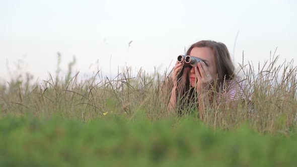 Beautiful Young Girl Looking Through Binoculars On Blue Sky Background.
