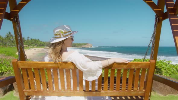 Slow Motion Woman in White Hat with Frangipani Flowers Swinging at Island Beach