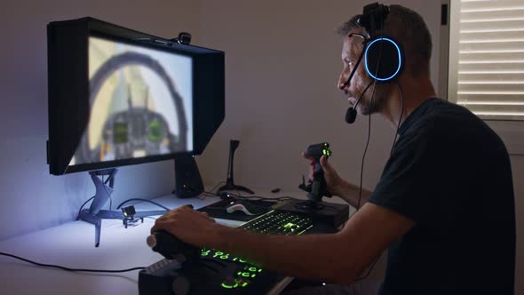 Man playing a flight simulator on the computer, wearing a headset