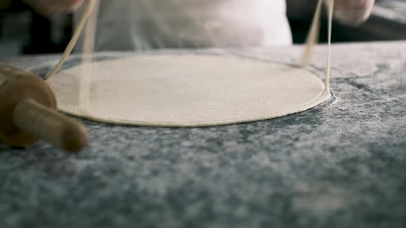 The Chef Cuts the Edges of the Roundshaped Dough with a Special Roller