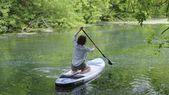 Young Woman with Curly Hair Sailing in the River on the Board