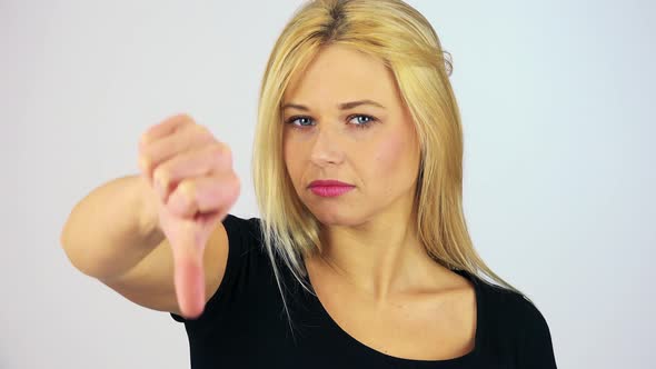 A Young Attractive Woman Shows a Thumb Down To the Camera - Face Closeup - White Screen Studio