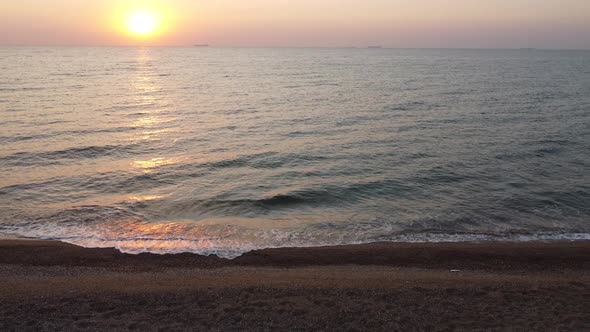 Sunrise and waves on the sea, view from the sandy beach