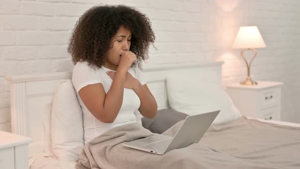 Young African Woman with Laptop Coughing in Bed