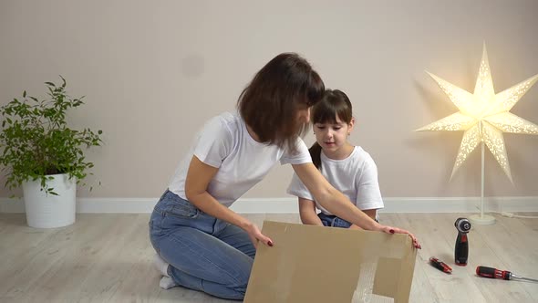 Happy Family Mother and Daughter Unpack New Wooden Furniture Together