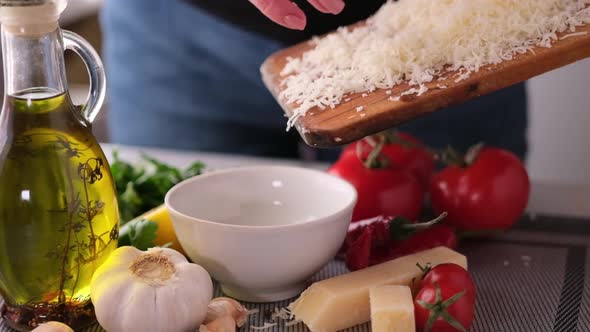 Woman Pours Grated Parmesan Cheese Into Ceramic Bowl