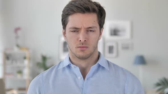 Portrait of Sad Handsome Young Man Looking at Camera