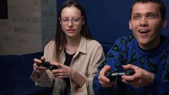 Happy Young People Playing Video Games on Console While Sitting on Couch in Front of Tv. Millennial