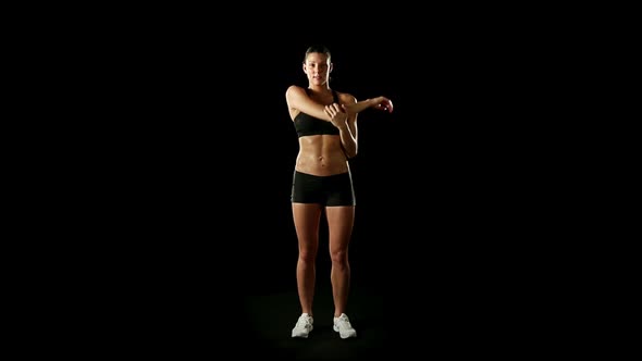 Young Athletic Woman Wearing Sporstwear is Warming Up Isolated on Black