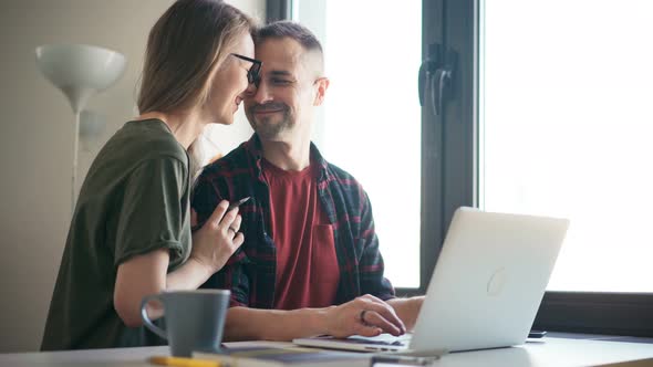 Happy Young Adult Couple Using a Laptop Doing Online Shopping Together