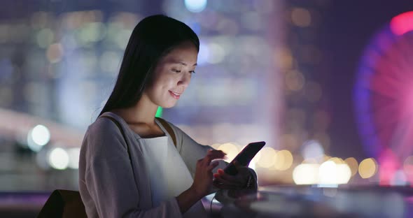 Woman look at smart phone in city at night