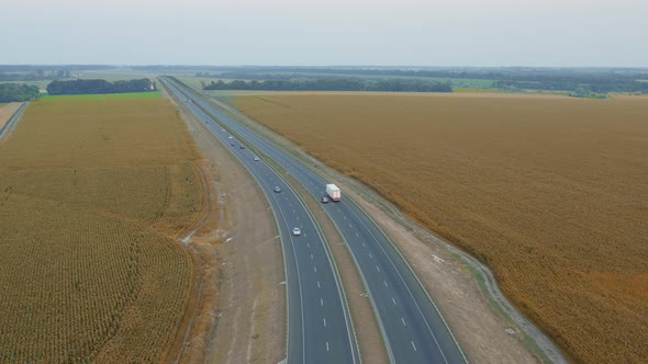 White Truck with Trailer Moves Along the Autobahn Among Fields with Wheat  Aerial Shot