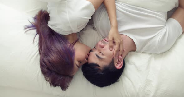 Happy Asian husband and pregnant wife spend time together in the bedroom in the morning.