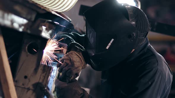 Male Worker at a Welding Factory in a Welding Mask