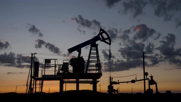 Oil Rig Stands in a Field at Sunset and Extracts Minerals