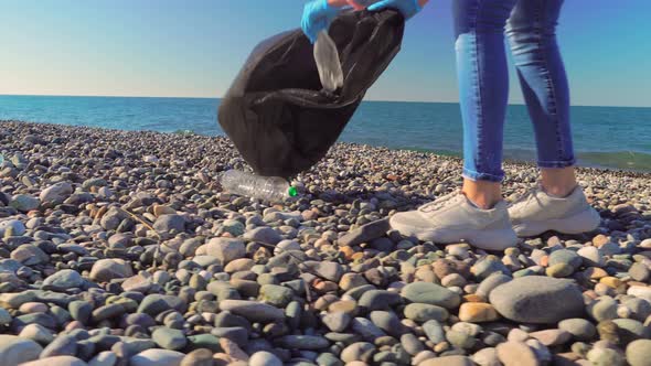 a woman collecting cleaning plastic bottles on the beach,