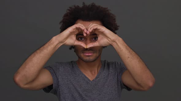 African American Cool Man Making Heart with Hands Enjoying Time Isolated on Charcoal Background