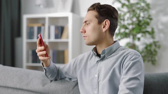 Happy Man Using Smartphone on Couch