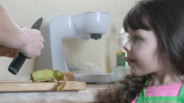 Vitaminized food for kids. Women's hand peels off a kiwi. 