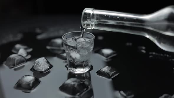 Pouring Up Shot of Vodka Into Glass. Black Background. Pour of Alcohol Drink