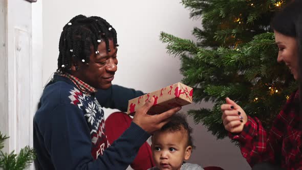 Multiracial Family Celebrating Christmas By Giving Each Other Beautifullywrapped Gifts