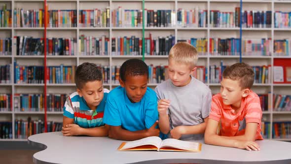 School kids reading book together in library alt