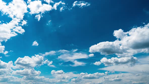 White Fluffy Clouds Slowly Float Through the Blue Daytime Sky Timelapse