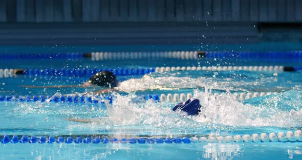 Man and woman swimming together inside the pool 4k