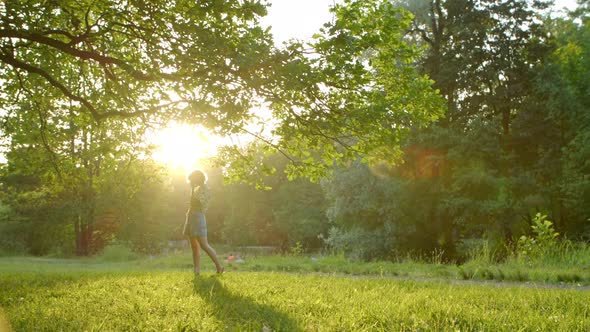 a Woman in the Light of the Departing Sun Stands Under a Beautiful Tree and Straightens Her Hair